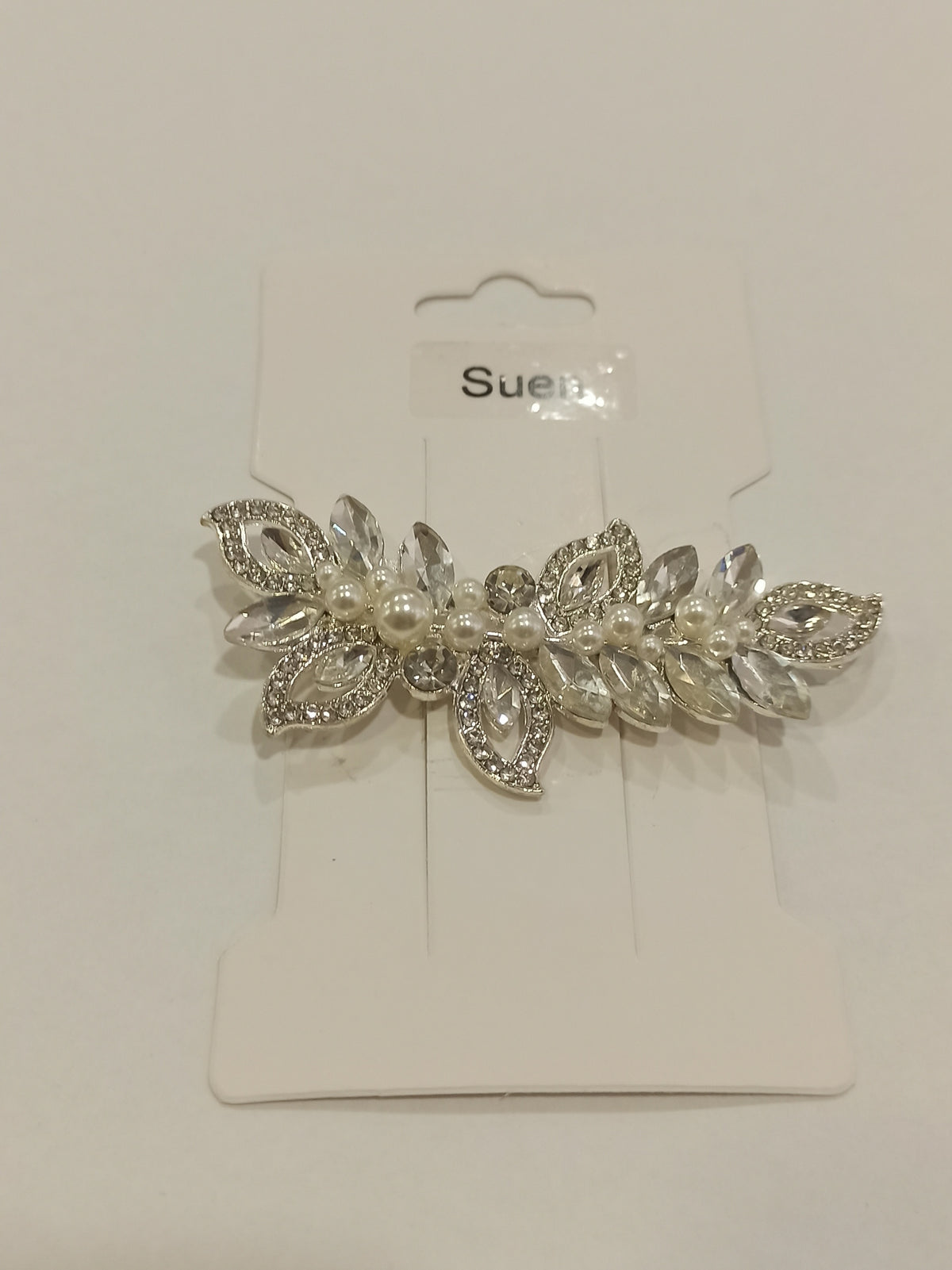 Clip floral plateado con perlas y cristales sobre su soporte