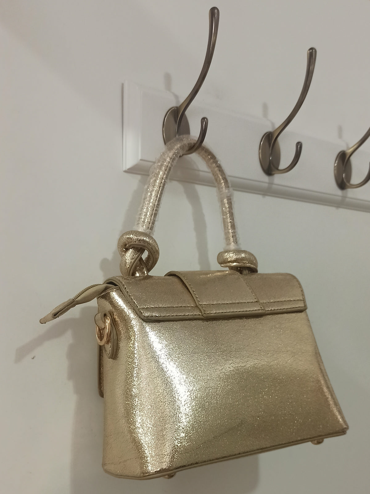 Bolso de fiesta dorado con asa de nudos y cierre decorativo