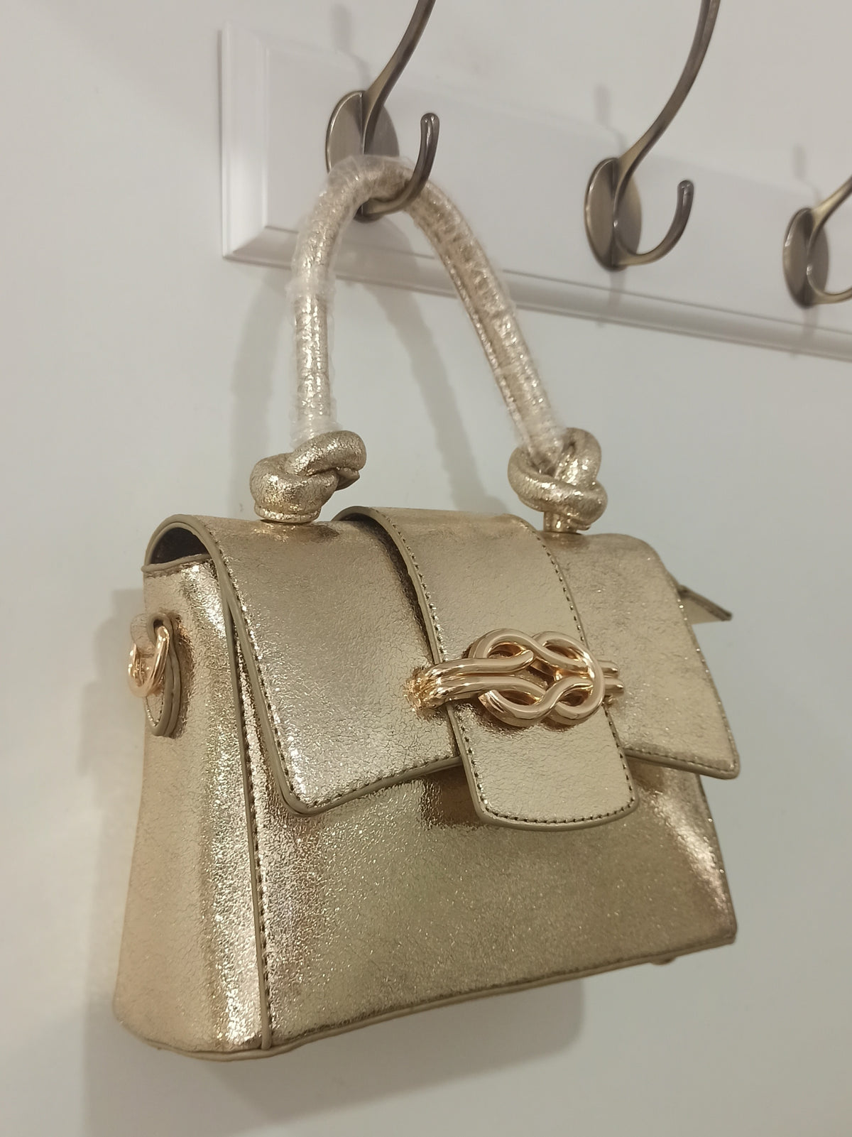 Bolso de fiesta dorado con asa de nudos y cierre decorativo