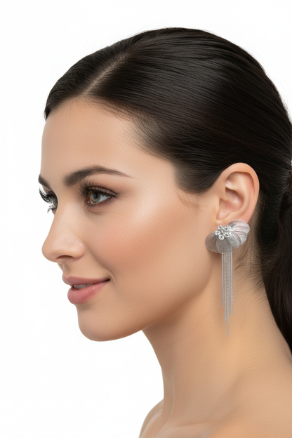 Modelo real de perfil con sonrisa y mirada pícara llevando pendientes largos plateados de 6 cm